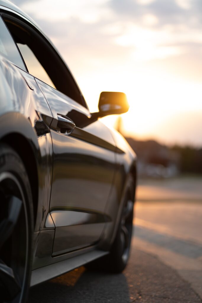Black car on road with sunset in the background